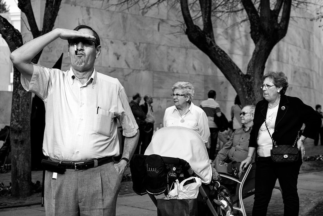 A man shielding his eyes from the sun beside other people.